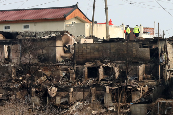 Police officers on Monday examine a village in Donghae, Gangwon, in which many houses were engulfed by a wildfire over the weekend. Firefighting authorities on Monday mobilized all available manpower and equipment to contain the main blazes in the eastern coastal areas hit by massive wildfires for the fourth day, as strong winds showed signs of fading. No casualties were reported, but 512 facilities, including 343 homes, have been damaged by the wildfires, the agency said, noting the affected areas include Uljin, Samcheok, Gangneung, Donghae, Yeongweol and Daegu's Dalseong County. The government on Monday issued a statement to the public, urging the people to be very careful not to inadvertently start a forest fire and vowing severe punishment for any who cause a fire intentionally or by negligence. [NEWS1]
