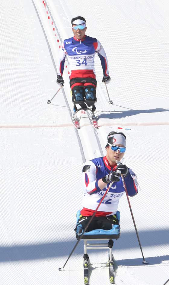 Shin Eui-hyun, back, and Won Yoo-min race in the para biathlon men's sitting middle distance race at the National Biathlon Centre in Beijing on Tuesday. [NEWS1]