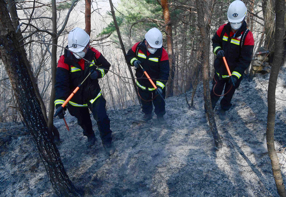 Navy personnel dispatched to Donghae, Gangwon, inspect scorched ground to ensure the fire had been completely extinguished in the area on Wednesday. [YONHAP]