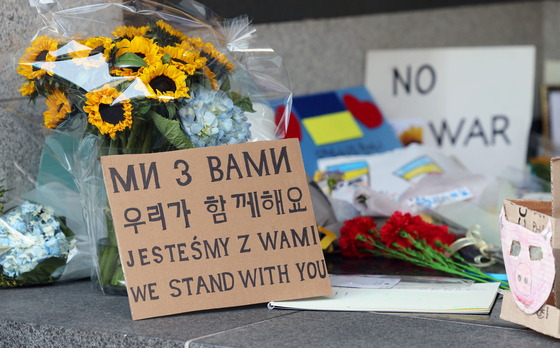 Flowers and signs supporting Ukraine in its war against Russia are seen outside the Ukrainian Embassy in Yongsan District, central Seoul, Thursday. [YONHAP] 