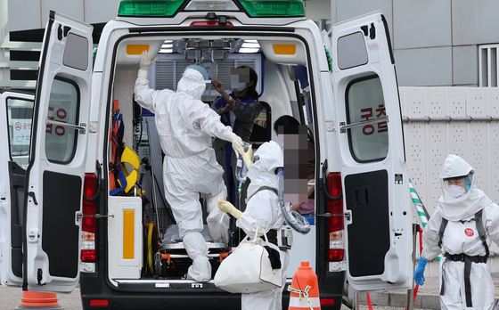 Medical workers in protective gear help a Covid-19 patient out of an ambulance at Seoul Medical Center in Jungnang District, eastern Seoul, on Thursday. [YONHAP]