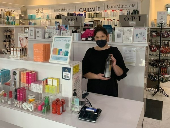 An employee at Planet Beauty, a beauty retailer based in California, holds up Moda Moda's Pro-Change Black shampoo. [MODA MODA]