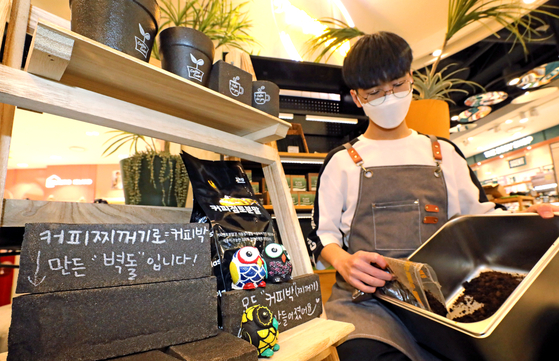 An employee gathers spent coffee grounds at Coffeebak Exchange, a coffee recycling store, at Hyundai Department Store's Sinchon branch in Mapo District, western Seoul, Tuesday. Coffee grounds, which had been classified as unrecyclable waste in the past, were recategorized as recyclable waste by the Ministry of Environment, starting from Tuesday. [NEWS1]