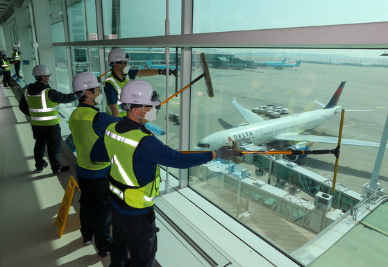 Janitors clean windows at Terminal 2 of Incheon International Airport on Tuesday as the airport management corporation prepares for more incoming passengers if the Covid-19 pandemic improves. [NEWS1]