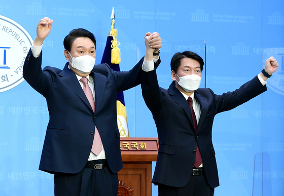 Yoon Suk-yeol, left, presidential candidate for the main opposition People Power Party, and Ahn Cheol-soo of the People's Party, announce an electoral alliance at the National Assembly in western Seoul on March 3. [NEWS1] 