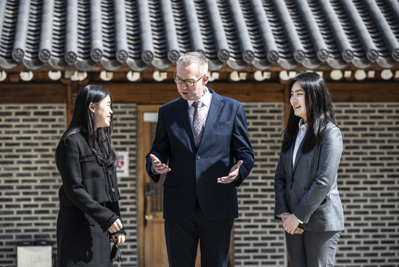 Colin Crooks, the British ambassador to Korea, center, speaks with winners of the International Women's Day Essay Writing Competition, Park Se-yeon, left, and Park Eo-jin, right, at the British Embassy in Seoul on Wednesday. [KIM HYUN-DONG]