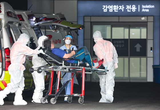 Paramedics and medical staff transfer a patient to an infectious diseases ward at Seoul Medical Center in Jungnang District, eastern Seoul, on Thursday, as the country reported a record-high number of Covid-19 cases, 621,328. [YONHAP]