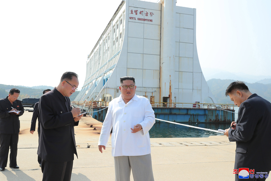 Dressed in white, North Korean leader Kim Jong-un visits the Mount Kumgang tourist resort in an undated photo released by Korean Central News Agency on Oct. 23, 2019. The rust-covered Haegumgang Hotel is seen in the background. [YONHAP]