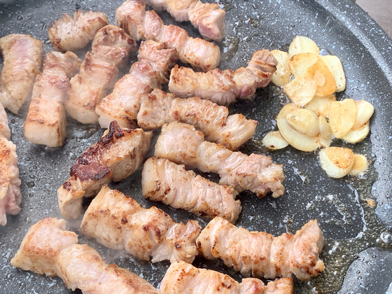 Samgyeopsal abd some garlic on the grill at Jamdubong The Nine in Mapo District, western Seoul [LEE JIAN]