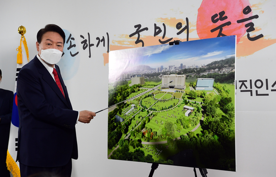 President-elect Yoon Suk-yeol points to the Defense Ministry main building in Yongsan District, where the presidential office will be relocated to, in a press conference at his transition team's headquarters in Samcheong-dong, central Seoul, Sunday. [JOINT PRESS CORPS]