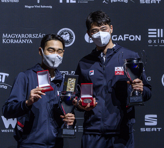 Kim Jung-hwan, left, and Oh Sang-uk pose with their trophies on the podium after sharing third place in the men's sabre World Cup in Budapest, Hungary, on Saturday. [EPA/YONHAP]