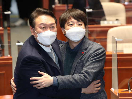 People Power Party (PPP) presidential candidate Yoon Suk-yeol, left, and PPP chief Lee Jun-seok embrace after a surprise reconciliation at the National Assembly in western Seoul Thursday evening. [NEWS1]
