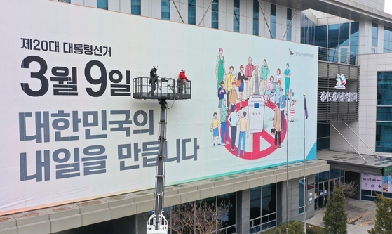Workers complete a billboard promoting the presidential election day – March 9 – on the Gyeonggi branch of the National Election Commission in Suwon, Gyeonggi, on Monday, 30 days ahead of the polling date, to encourage voters to cast ballots. [YONHAP]
