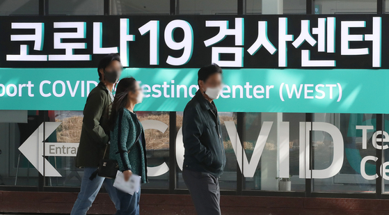 People pass in front of a Covid-19 testing center at Incheon International Airport on Tuesday. [NEWS1]