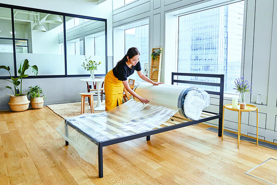 A model places Zinus's mattress on a bed frame. [ZINUS]