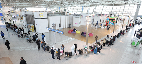 Passengers wait in long lines to check in at the boarding area at Terminal 1 of Incheon International Airport on Sunday. Since the Korean government did away with a mandatory seven-day quarantine for vaccinated arrivals from other countries starting March 21, international travelers have drastically increased, according to travel agencies.  [YONHAP]