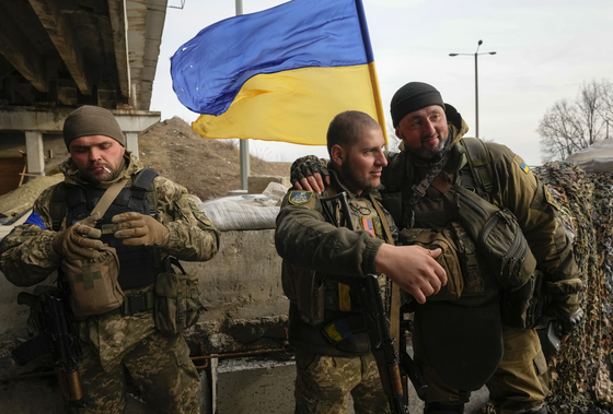 Ukrainian soldiers chat in front line position close to Kharkiv, Ukraine, on March 26. With the invasion now in its second month, Russian forces have reportedly stalled on many fronts and are even losing previously taken ground to Ukrainian counterattacks, including around Kyiv. [AP/YONHAP] 