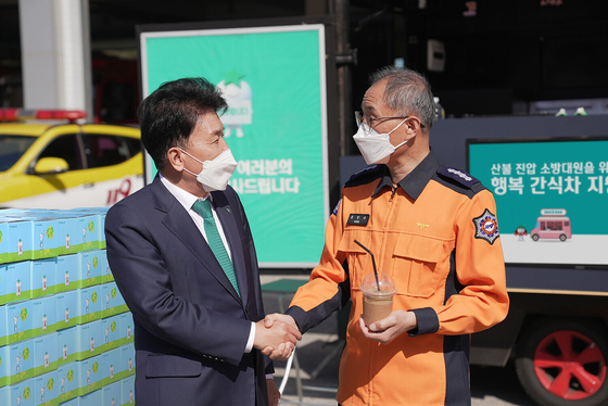 Hana Financial Group Chairman Ham Young-joo, left, shakes hands with Song In-su, chief of Uljin Fire Station, who was in charge of the firefighters who put out a wildfire that engulfed a wide range of mountains in the eastern region of Korea from March 4 to 13. [NEWS1]