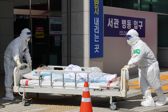 Medical professionals transfer a Covid-19 patient to Seoul Seobuk Hospital in Eunpyeong District, northern Seoul, Tuesday. [YONHAP]