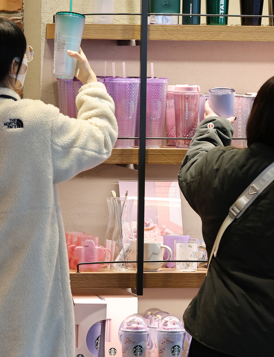Customers look at tumblers at a franchise coffee shop in central Seoul on Thursday. Customers will not be able to use disposable cups when drinking inside cafes starting on April 1. [YONHAP]