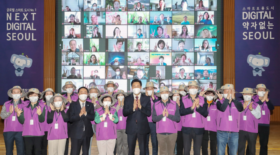 Seoul Mayor Oh Se-hoon, center, poses for a group photo with digital supporters for senior citizens at City Hall on Thursday. Digital supporters, who are aged 55 or older, will teach the elderly how to use digital devices. [NEWS1]