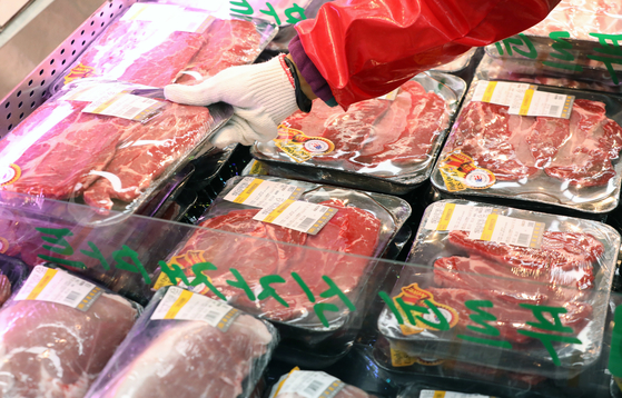 An employee displays imported meat packs at a mart at Eungam-dong, northern Seoul, in December. [NEWS1] 
