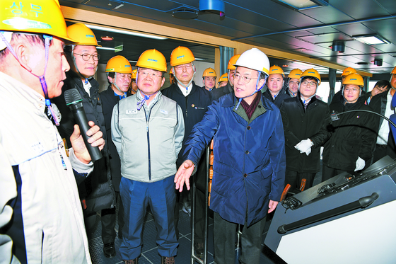 President Moon Jae-in, front row center, listens to Park Doo-seon, left, a managing director at Daewoo Shipbuilding & Marine Engineering (DSME), at DSME's Okpo shipyard in Geoje, South Gyeongsang, in January 2018. [JOINT PRESS CORPS]