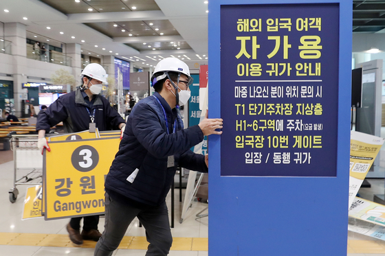 Airport staffers remove signs for quarantine taxis and buses at the arrival hall at Incheon International Airport, on Friday, after the government lifted most measures on foreign travelers. All fully vaccinated travelers from abroad can enter the country without a seven-day quarantine period and can also take public transportation. [NEWS1]