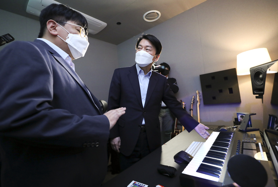 Ahn Cheol-soo, right, chairman of President-elect Yoon Suk-yeol's transition team, converses with Bang Si-hyuk, founder and chairman of HYBE, the management agency of K-pop group BTS, in the company's office in Seoul on Saturday. [YONHAP]