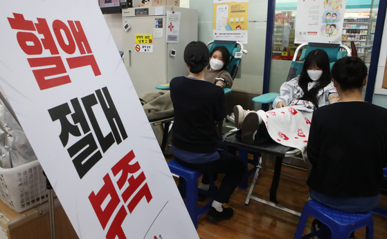Students at Dong-Eui Institute of Technology in Busan donate blood last month on campus near a sign that roughly translates as “absolute lack of blood.” [SONG BONG-GEUN]