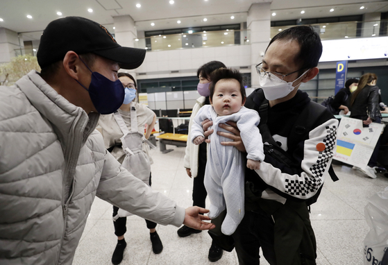 A Ukrainian-Korean man from Odessa, Ukraine, with a baby, right, greets his friend in Korea upon arrival at the Incheon International Airport on March 30. [YONHAP]