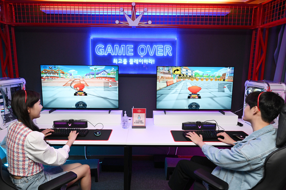 Models play games at LG Electronics’ newly opened game room in Busan on Wednesday. Visitors will be able to play games on its OLED television through June 5. [YONHAP]