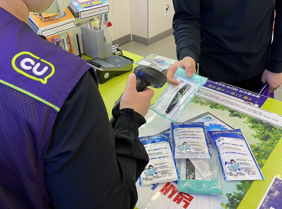 A customer purchases Covid-19 test kits at a CU convenience store. The convenience store franchise is lowering its price of six different types of Covid-19 test kits by 16 percent to 5,000 won ($4) per kit starting on Thursday. [YONHAP]