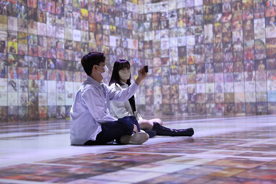Visitors look at a media art display at Ground Seesaw Myeongdong in Jung District, central Seoul, on Thursday. Lotte Department Store opened an exhibition dubbed "Poetic AI" that day at its main branch in Myeong-dong, to run through Oct. 6. [YONHAP]