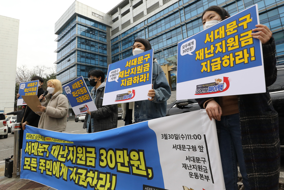 People are holding a press conference asking the Seodaemun District Office to dole out relief funds to 3,000 residents in front of the office on March 30. [NEWS1]