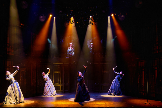 Four female cast members singing into standing microphones during a scene from the musical "Lizze" [SHOWNOTE]