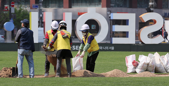 Workers lay down the lawn on Seoul Plaza in front of Seoul City Hall on Tuesday, in preparation for spring. The Seoul Metropolitan Government announced that it will be hosting “Read at Seoul Plaza” starting from Saturday, World Book Day, where citizens can comfortably read books on the grass of Seoul Plaza using beanbags and mats. The event will be held every Friday and Saturday from 11 a.m. to 4 p.m. [NEWS1]