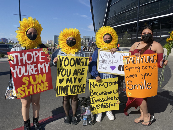 Members of ARMY stand outside of the Allegiant Stadium on April 9 with signs. [YONHAP]