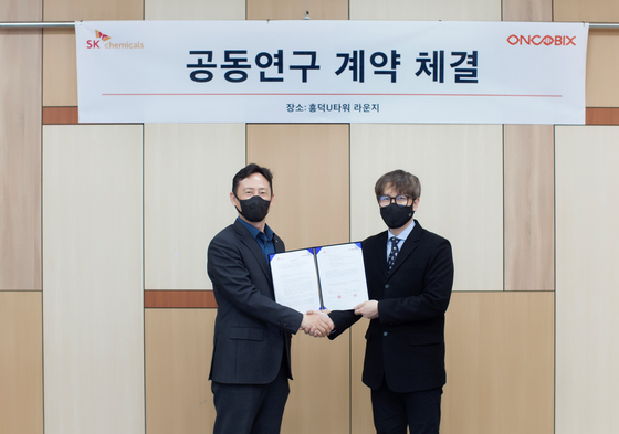 Kim Jeong-hoon, left, head of SK Chemicals' pharmaceutical research and development center, and Kim Sung-eun, CEO of Oncobix, shake hands after signing an agreement to cooperate on developing new drugs at the venture's headquarters in Yongin, Gyeonggi. [SK CHEMICALS]