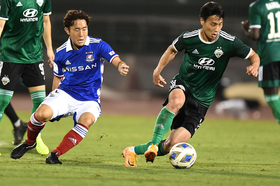Yokohama F.Marinos' Kouta Watanabe, left fights for the ball with Jeonbuk Hyundai Motors' Paik Seungho during an AFC Champions League Group H match at the Thong Nhat Stadium in Ho Chih Minh City on Tuesday. [AFP/YONHAP]