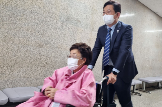 Song Young-gil, chairman of the ruling Democratic Party (DP), pushes Lee Yong-soo, a Japanese wartime sexual slavery survivor, in a wheelchair following their meeting at the National Assembly in western Seoul Tuesday. [YONHAP]