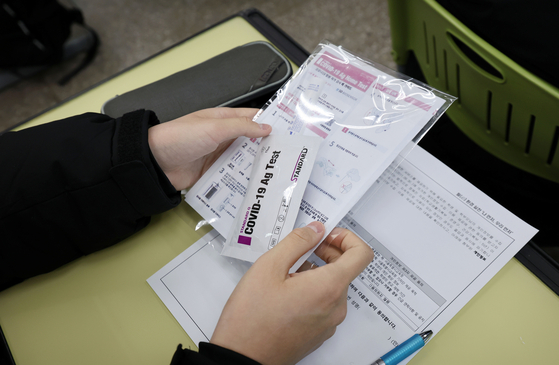 A Dogok Middle School student looks at a Covid-19 rapid antigen self-test kit in Gangnam, southern Seoul, on March 2. [YONHAP]