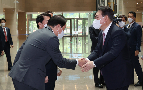 President-elect Yoon Suk-yeol, right, shakes hands with SK Group Chairman Chey Tae-won during his visit to SK bioscience headquarters in Seongnam, Gyeonggi, on Monday. [YONHAP]
