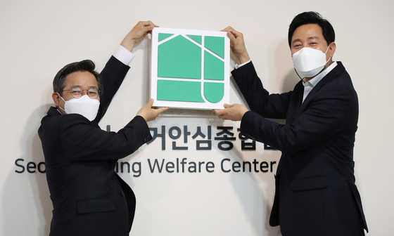 Seoul Mayor Oh Se-hoon (right) and Seoul Housing and Communities Corporations (SH) CEO Kim Heon-dong, hang a signboard during a ceremony at the Seoul Housing Welfare Center Yongsan, the city's first housing assistance center, on Monday. [NEWS1]