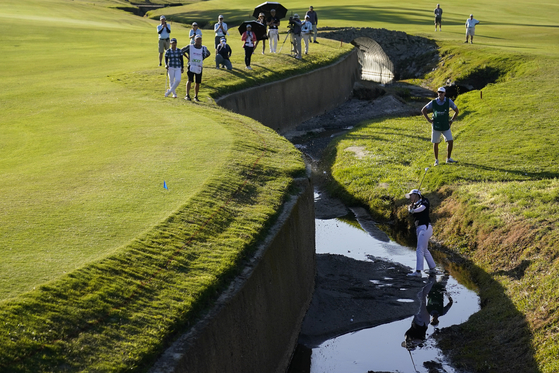 Ko Jin-young hits from a creek bed between the 17th and 18th holes during the third round of LPGA's DIO Implant LA Open golf tournament at Wilshire Country Club on Saturday in Los Angeles. Her ball hit the wall and bounced back twice. [AP/YONHAP]