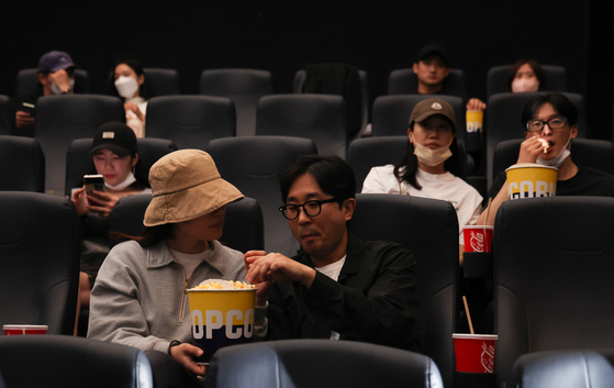 Audience members eat snacks inside a movie theater in Mapo District, western Seoul, on Monday, as Korea eased restrictions on eating and drinking on public transit, in theaters, religious houses and indoor stadiums. [WOO SANG-JO]