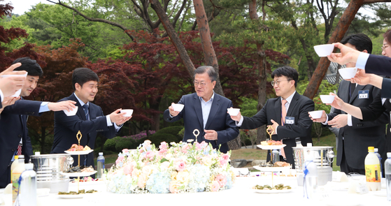 President Moon Jae-in, center, toasts to reporters in his final press conference at the Nokjiwon presidential garden in the Blue House in central Seoul Monday afternoon two weeks before the end of his five-year term. [JOINT PRESS CORPS]