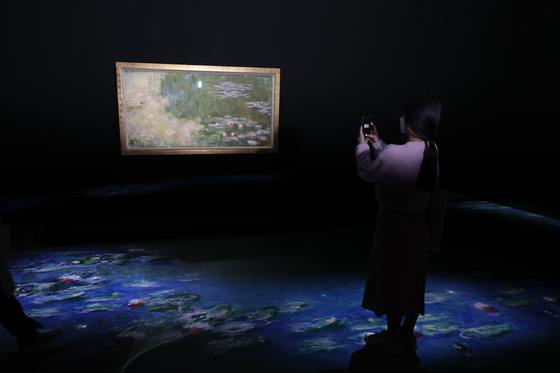 A visitor takes a picture of Claude Monet’s “The Water-Lily Pond." [YONHAP]