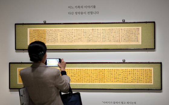 A visitor takes a picture of a pair of scrolls with writings by Joseon-era (1392-1910) scholar Jeong Yak-yong (1762-1836), commissioned by Jeong’s neighbor in Gangjin. The scrolls are on public viewing for the first time. [YONHAP]