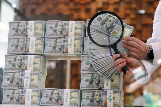 An employee inspects dollar bills for forgery at Hana Bank in central Seoul on Thursday. The Korean won continued to depreciate against the dollar the same day, settling at 1,272.5 won per dollar, a record low in more than two years since it reached 1,282.5 won per dollar during trading on March 23, 2020. [NEWS1]